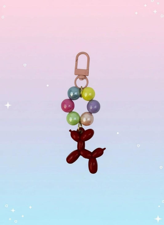 Keychain with colorful beads and a red balloon dog charm on a white background