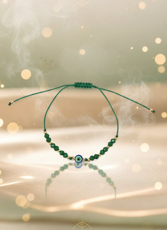 Green beaded bracelet on a cardboard holder against a light gray background