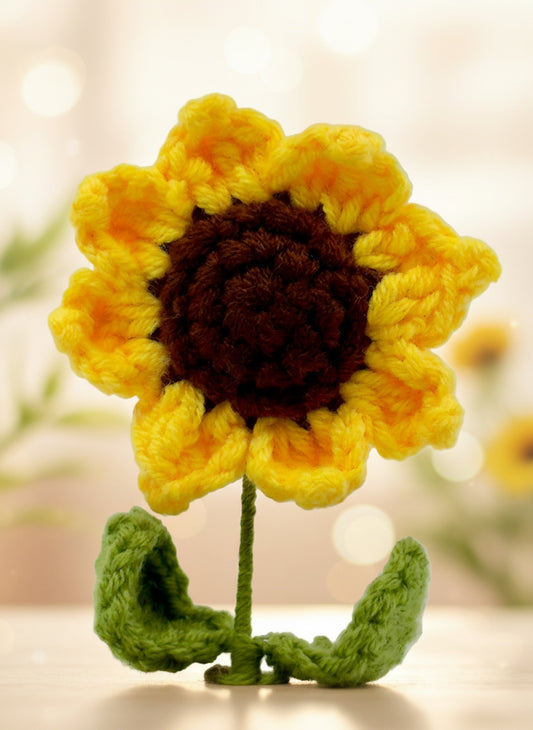 Crocheted sunflower with yellow petals and a brown center on a light gray background