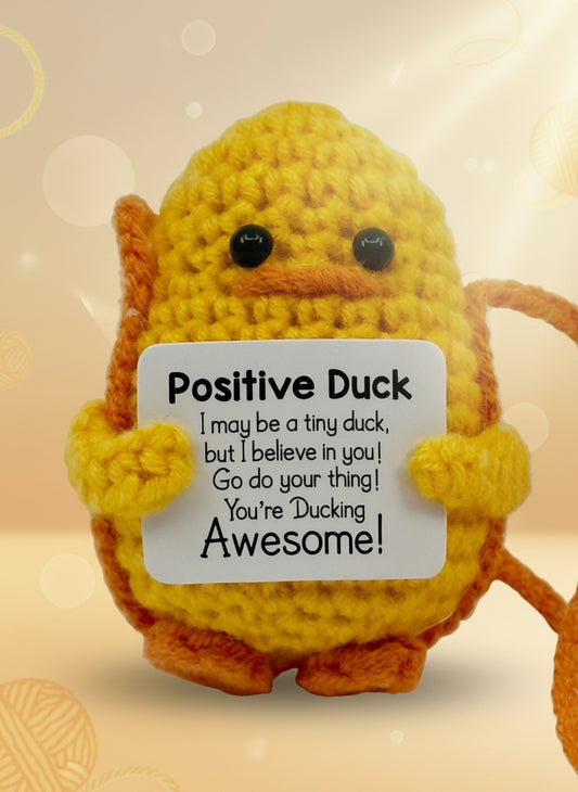 Crocheted duck holding a sign with motivational text on a white background