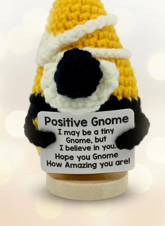 Crocheted gnome with a sign reading 'Positive Gnome' on a white background