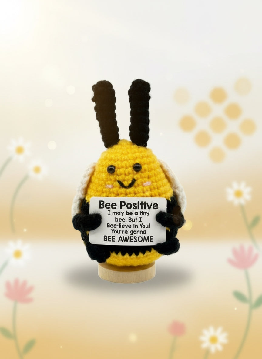 Crocheted bee holding a sign with text on a white background