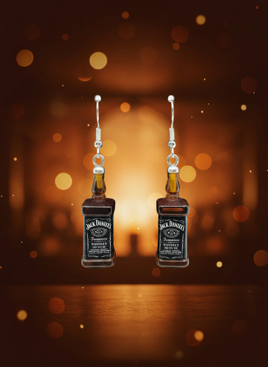 Jack Daniel's bottle-shaped earrings on a black card with a wooden stand.