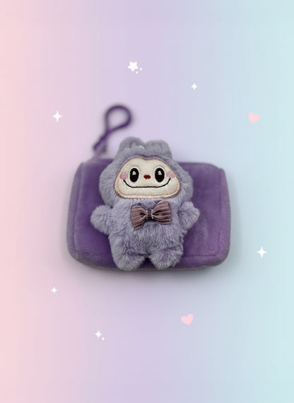 Plush toy with a bow tie on a purple pouch against a light gray background
