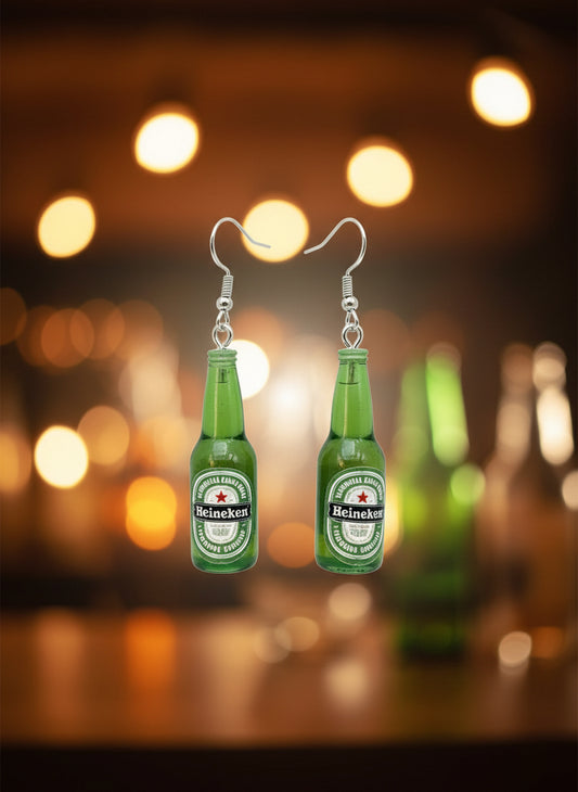 Green bottle-shaped earrings on a black card with a wooden stand against a white background
