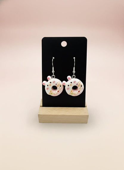 Cute Animal Donut Earrings displayed on a stand, featuring colorful animal faces in donut designs.