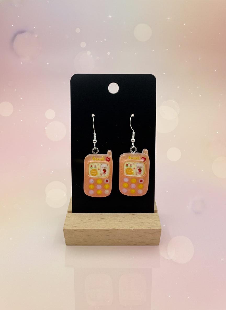 Adorable Kawaii Phone Earrings displayed on a wood stand, showcasing cute resin cartoon phone design in pastel colors.