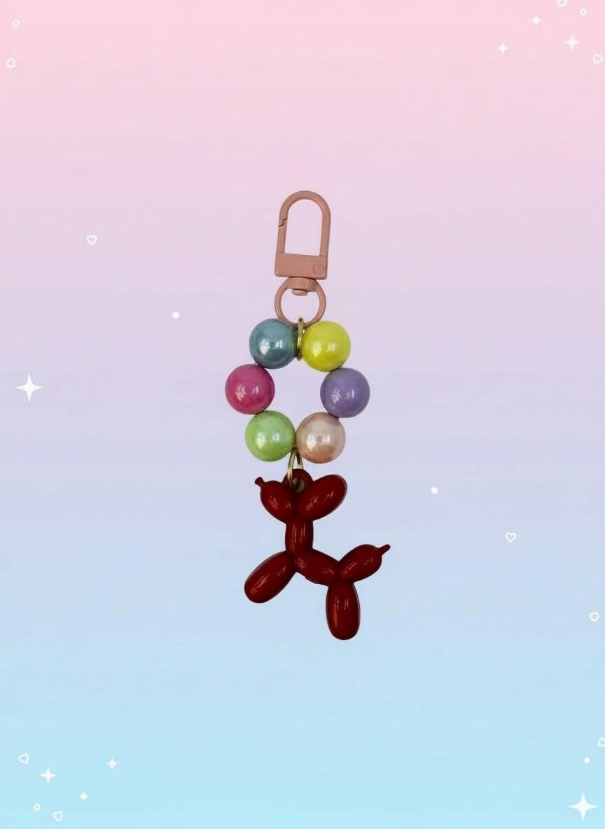 Keychain with colorful beads and a red balloon dog charm on a white background