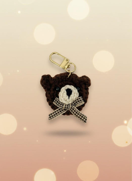 Brown teddy bear keychain with a bow on a light gray background