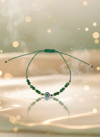 Green beaded bracelet on a cardboard holder against a light gray background