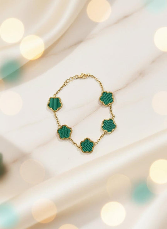 Green necklace with gold chain on a brown card against a white background