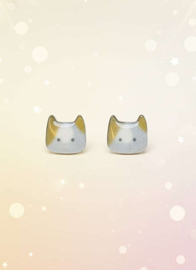 Cat-shaped earrings on a black card with a wooden stand against a white background