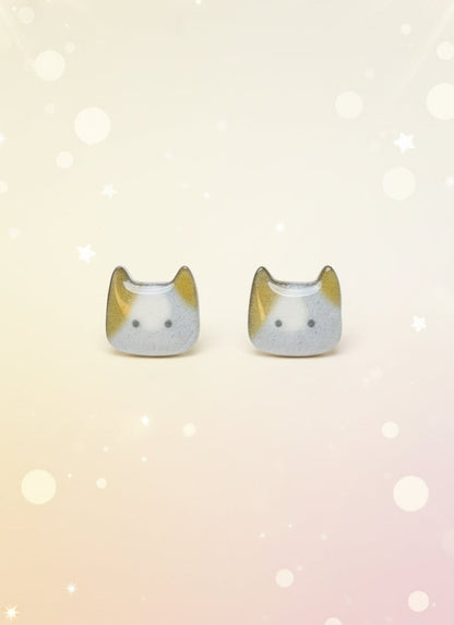Cat-shaped earrings on a black card with a wooden stand against a white background