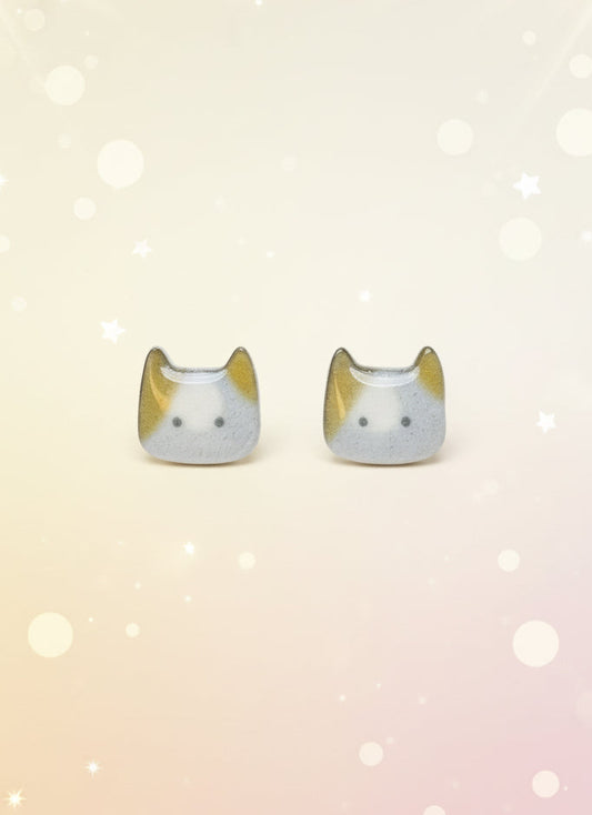 Cat-shaped earrings on a black card with a wooden stand against a white background
