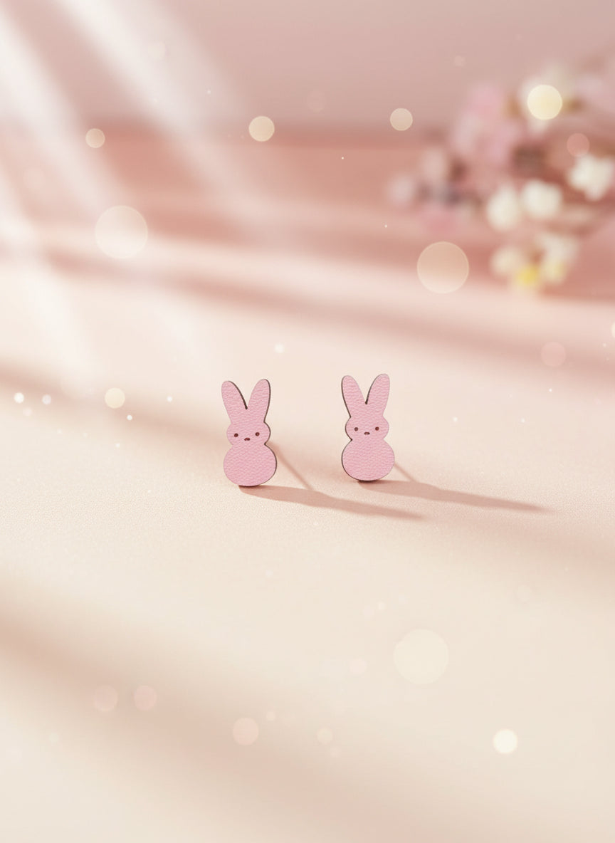 Pink bunny-shaped earrings on a black card with a white background