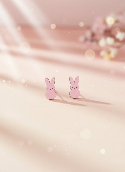 Pink bunny-shaped earrings on a black card with a white background
