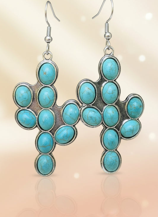Turquoise stone earrings on a wooden stand with a black background