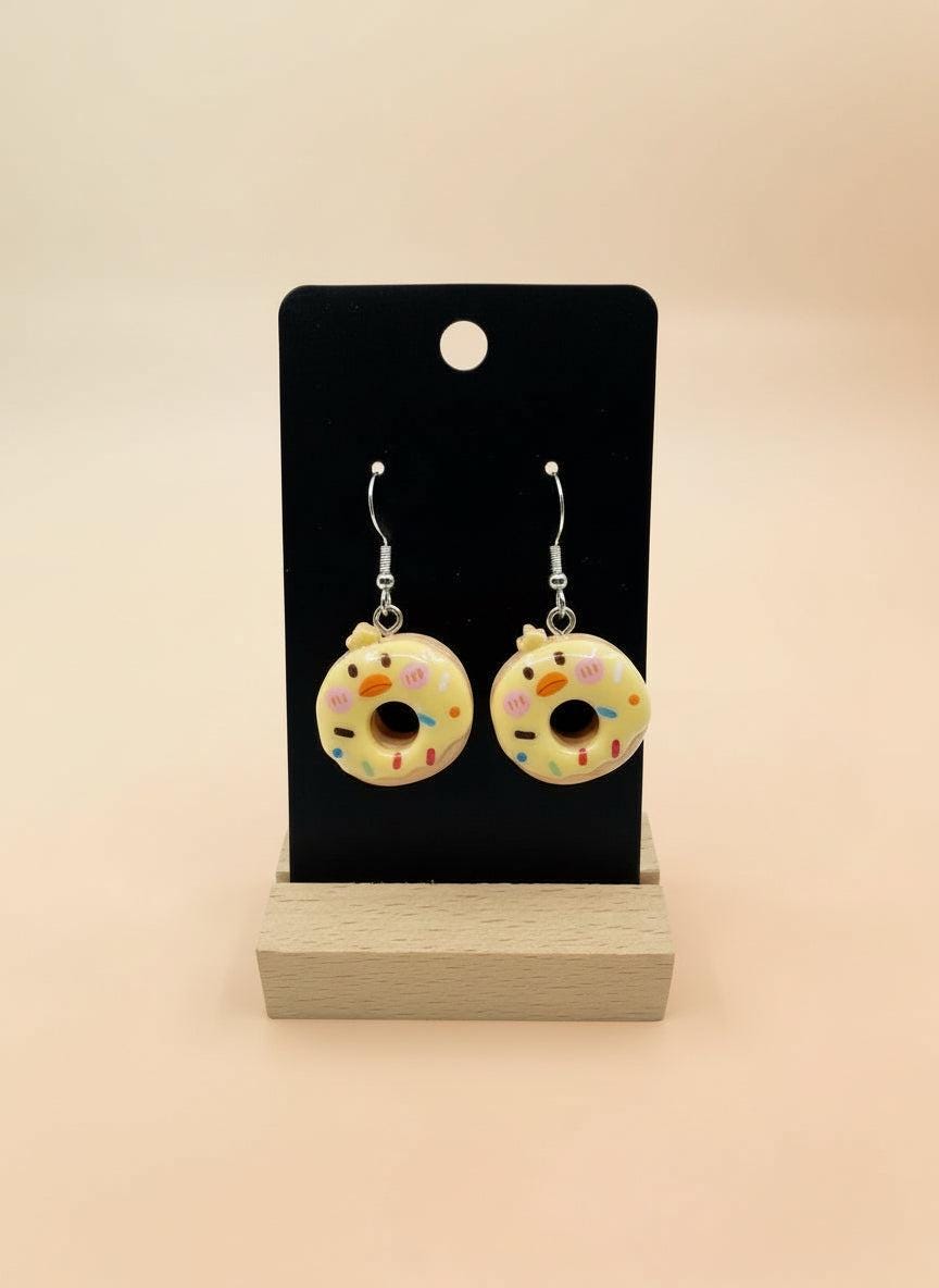 Cute Animal Donut Earrings displayed on a stand with colorful donut designs and animal faces, handmade resin charm jewelry.