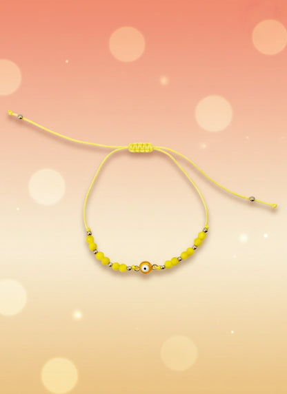 Yellow beaded bracelet on a cardboard holder against a white background
