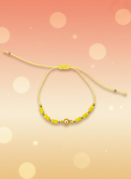 Yellow beaded bracelet on a cardboard holder against a white background