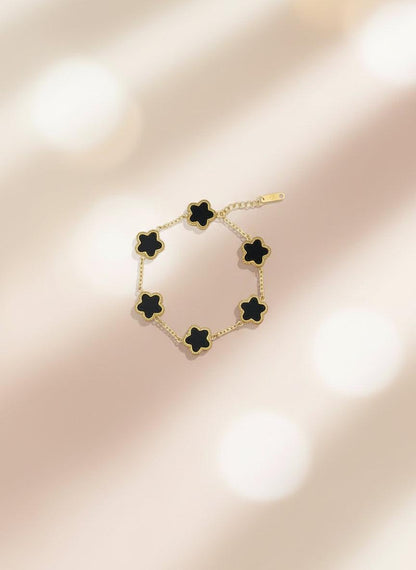 Bracelet with black flower-shaped ends on a cardboard holder against a white background