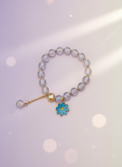 Bracelet with purple beads and a blue flower charm on a white background