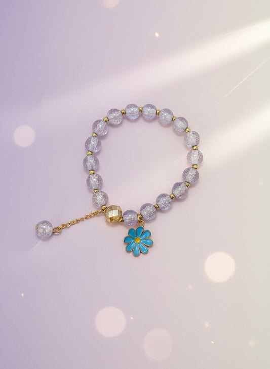Bracelet with purple beads and a blue flower charm on a white background