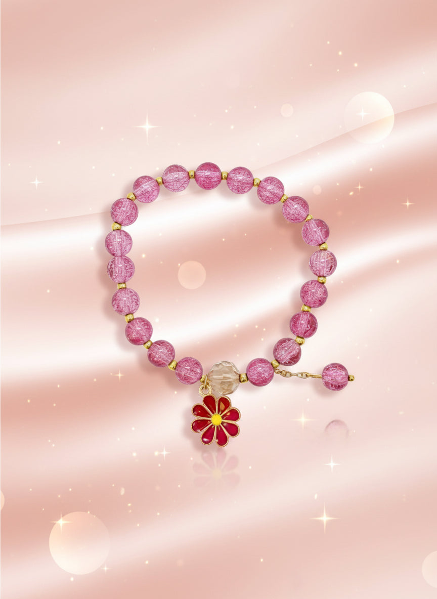 Pink beaded bracelet with a floral charm on a cardboard stand against a white background
