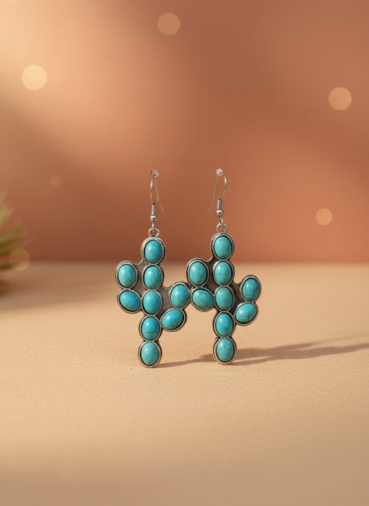 Turquoise earrings on a black card with a wooden stand against a white background