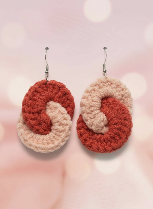 Two knitted keychains with a heart design on a colorful background