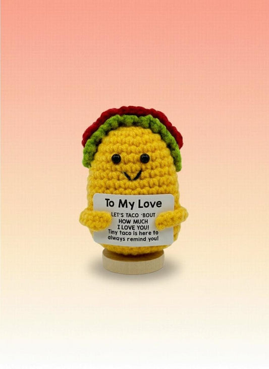Crocheted taco-shaped object with a message on a white background