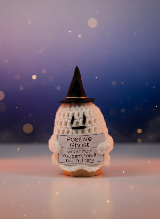 Small knitted ghost figurine with a black hat and a sign reading &#39;Positive Ghost&#39;.