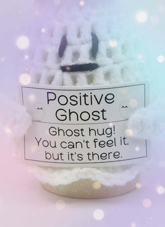 Crocheted ghost with a label reading &#39;Positive Ghost&#39; on a white background